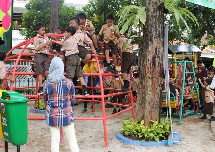 Indonesian school children in scout uniforms play on the jungle gym at a Bakti Barito-supported Ruang Publik Terbuka Ramah Anak (RPTRA) community center in Jakarta.