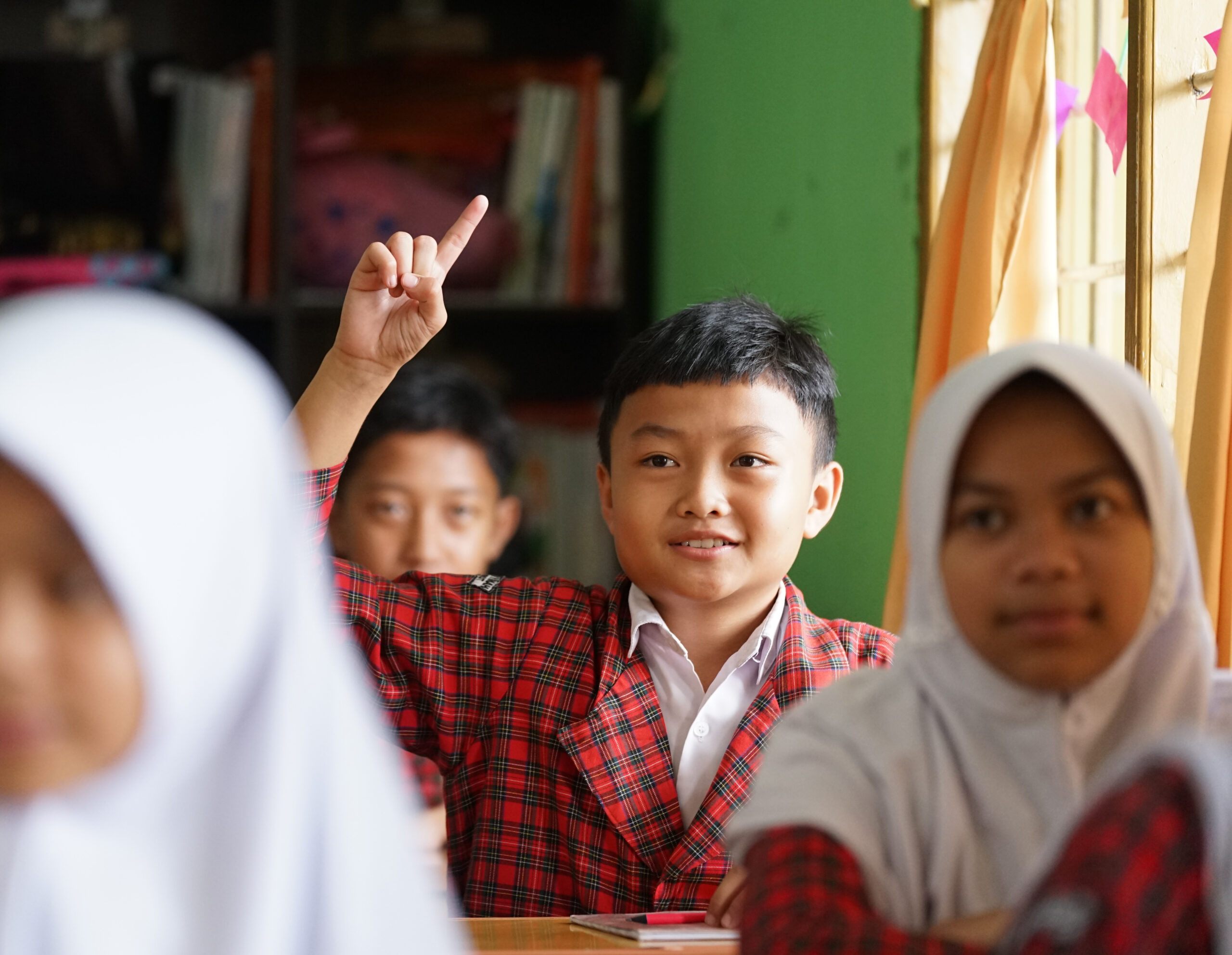 An engaged young student raises his hand to participate in the Green Guardians classroom program, an environmental education initiative by Bakti Barito.
