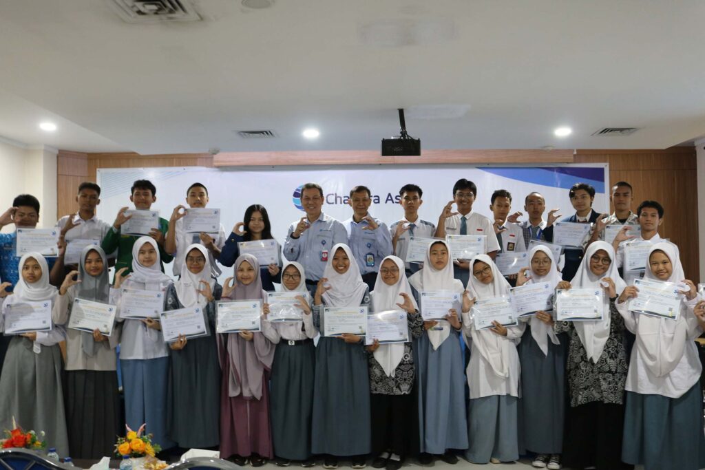 Chandra Asri Group President Director Scholarship: students in a blue patterned school uniform receives a merit-based scholarship certificate from company representatives during a formal ceremony.